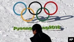 FILE - A man walks by the Olympic rings with a sign of 2018 Pyeongchang Olympic Winter Games, in Pyeongchang, South Korea, Feb. 3, 2017. 