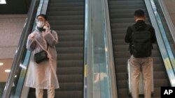 25일 한국 인천 국제공항에서 보호장비를 착용한 여성이 에스컬레이터를 타고 내려오고 있다. 