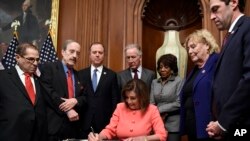 House Speaker Nancy Pelosi signs the resolution to transmit the two articles of impeachment against President Donald Trump to the Senate for trial on Capitol Hill in Washington, Jan. 15, 2020. 