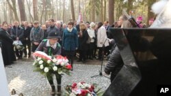 A girl scout lays a wreath at the central monument of a cemetery near the village of Jagiella, in southern Poland, Thursday, March 17, 2016 during ceremonies remembering the Ulma family and eight Jews they were sheltering during Holocaust, all of whom wer