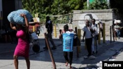 Sejumlah warga pergi meninggalkan tempat tinggal mereka dengan membawa barang bawaan masing-masing menyusul serangan geng bersenjata ke salah satu wilayah di Port-au-Prince, Haiti, pada 19 November 2024. (Foto: Reuters/Ralph Tedy Erol) 