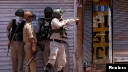 Seorang polisi India menggunakan ketapel untuk melemparkan batu ke arah para pemrotes saat terjadi bentrokan pada peringatan pembunuhan pasukan India Burhan Wani, komandan kelompok militan Hizbul Mujahidin, di pusat kota Srinagar, 8 Juli 2017.