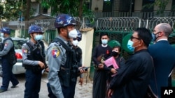 Myanmar police talk to people gathering outside the Kamayut court in Yangon, March 12, 2021. 
