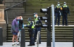 FILE - Police check details of residents in the Melbourne central business district in Australia's worst-hit Victoria state, Aug. 9, 2020, as the city struggles to cope with COVID-19 pandemic.