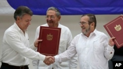 FILE - Colombian President Juan Manuel Santos, left, and Commander of the Revolutionary Armed Forces of Colombia, Timoleon Jimenez, right, shake hands during a signing ceremony of a cease-fire, June 23, 2016.