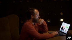 In this Nov. 30, 2016 photo, Laurynas Ragelskas searches on his computer, in Vilnius, Lithuania. Ragelskas is part of a wider effort by the tiny Baltic country to defend itself from what it says is an onslaught of Russian propaganda.