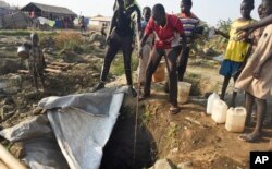 Displaced people draw water from a hole dug in the ground, in the United Nations camp for displaced people in the capital Juba, South Sudan, Jan. 19, 2016.