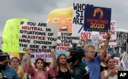 Protestors hold up anti President Donald Trump signs during a rally, June 18, 2019, in Orlando, Florida.