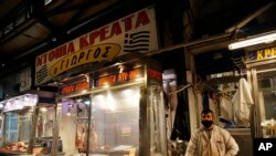 A butcher wearing a face mask to protect against coronavirus waits for customers at Varvakios meat market, usually busy during the Holy Week ahead of Orthodox Easter, in Athens, April 17, 2020.