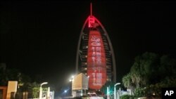 FILE - A sign reading "UAE Chinese Week" in Chinese and Arabic is projected onto the Bus Al Arab luxury hotel to celebrate the UAE Chinese Week in Dubai, July 18, 2018.