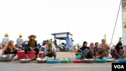 អ្នក​លក់​ត្រី​នៅ​ខាង​មុខ​កំពង់ចម្លង​ជ្រោយចង្វារ អង្គុយ​នៅក្បែរ​ក្មួយស្រី​នៅល្ងាចមួយ​កាលពី​ថ្ងៃទី​១៤ ខែតុលា ឆ្នាំ២០១៩។(ទុំ ម្លិះ/VOA)