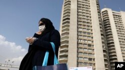 Seorang pejalan kaki mengenakan masker berjalan di utara Teheran, Iran, 1 Maret 2020. 