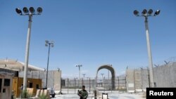 FILE - An Afghan National Army soldier stands guard at the gate of Bagram U.S. air base, on the day the last of American troops vacated it, Parwan province, Afghanistan, July 2, 2021. 