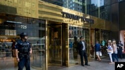 FILE - People pass police security an a building doorman in front of Trump Tower in New York.