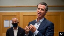 FILE - California Governor Gavin Newsom, right, speaks during a tour of a cooling center in Sacramento, California, Aug. 18, 2020. Newsom declared an emergency Tuesday over wildfires burning throughout the state.