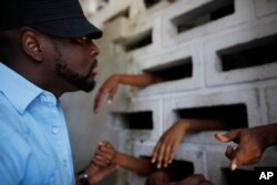 Haitian musician Wyclef Jean speaks to inmates at the women's annex of the National Prison in Port-au-Prince, June 16, 2010.