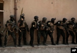 FILE - Soldiers from the 1st Battalion of the Iraqi Special Operations Forces are stacked against a building during a training exercise to prepare for the operation to retake Mosul from Islamic State militants, in Baghdad, Iraq, Aug. 13, 2016.