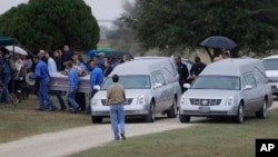 A casket is removed from one of two hearses during a grave side service for Richard and Therese Rodriguez at the Sutherland Springs Cemetery in Sutherland Springs, Texas, Nov. 11, 2017.