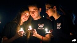 Attendees comfort each other at a candlelight vigil for the victims of the shooting at Marjory Stoneman Douglas High School, Feb. 15, 2018, in Parkland, Fla. 
