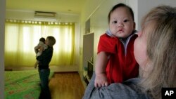 រូប​ថត​ឯកសារ៖ Monic​ DiGioacchino (ស្តាំ)​មក​ពី​ទី​ក្រុង​ Alameda​ រដ្ឋ​កាលីហ្វ័រញ៉ា សហរដ្ឋ​អាមេរិក លើក​បី​កូន​ចិញ្ចឹម​របស់​នាង​មក​ពី​​វៀតណាម​ ឈ្មោះ​ Patrick​ អាយុ​៧​ខែ​ ខណៈ​ពេល​ដែល​មិត្ត​រួម​បន្ទប់​របស់​នាង​ឈ្មោះ ​Tracy​ Sumner (រូប​ខាង​ក្រោយ)​ មក​ពី​ទី​ក្រុង​ Richmond ​រដ្ឋ​ Virginia​ ក៏​កំពុង​តែ​លើក​បី​កូន​ចិញ្ចឹម​​អាយុ​៥​ខែ​ នៅ​ក្នុង​ទី​ក្រុង​ហាណូយ​ប្រទេស​វៀតណាម។ 