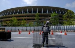 FILE - Workers install additional security fence outside Olympic Stadium (National Stadium) for the Tokyo Olympic Games, June 10, 2021.