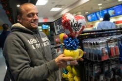 FILE - Mohammed Hafar buys a gift for his daughter Jana Hafar while waiting for her flight at JFK Airport in New York, Dec. 3, 2019.