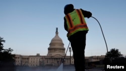 Seorang pekerja membersihkan trotoar di dekat Gedung Capitol di Washington, pada 28 September 2023. (Foto: Reuters/Jonathan Ernst)