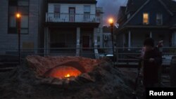Seorang warga Queens, Shane Decarolis, berdiri di dekat perapian di luar rumahnya (3/11). Sebagian listrik di wilayah New York, termasuk Queens dan Staten Island, hingga kini masih belum mendapat aliran listrik pasca hantaman badai Sandy.