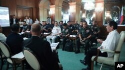 In this handout photo provided by the Malacanang Presidential Photographers Division, Philippine President Rodrigo Duterte, right, talks with security officials at the Malacanang presidential palace in Manila, Jan. 5, 2020. 