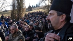 People pray during the funeral ceremony for Ukrainian army officer Vasyl Medviychuk in the Carpathian Mountains in Krasnyk, Ukraine, Dec. 29, 2023.
