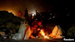 A man squats next to a fire, as Palestinians, who fled the eastern part of Khan Younis, were ordered by the Israeli army to evacuate their neighborhoods, amid the Israel-Hamas conflict, in Khan Younis, in the southern Gaza Strip, July 22, 2024.