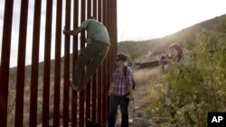 រូបឯកសារ៖ បុរស​ម្នាក់​បង្ហាញ​ពី​របៀប​ឡើង​លើ​របង​ដែល​ពុះ​ចែក​ព្រំដែន​ប្រទេស​ម៉ិកស៊ិក និង​ សហរដ្ឋ​អាមេរិក នៅ​ត្រង់​ចំណុច​បញ្ចប់​នៃ​របង​នេះ។