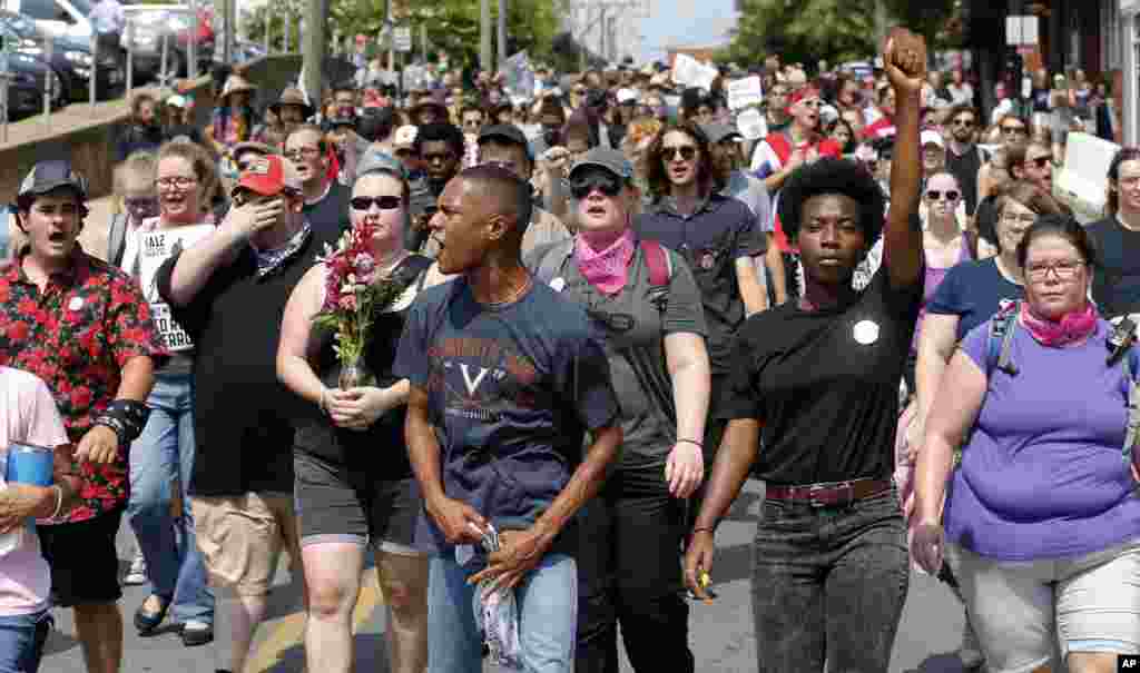 Demonstrators against racism march along city streets as they mark the anniversary of last year's Unite the Right rally in Charlottesville, Va., Sunday, Aug. 12, 2018.