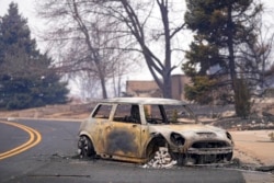 A charred Mini Cooper sits in the street, in Louisville, Colo., Dec. 31, 2021.