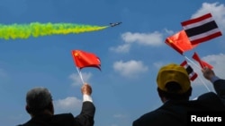 ผู้ชมถือธงชาติจีนและไทย ขณะร่วมชมแสดงการบินผาดแผลง เนื่องในโอกาสครบรอบ 88 ปีการก่อตั้งกองทัพอากาศไทย กรุงเทพมหานคร วันที่ 5 มีนาคม 2568 (ที่มา: Reuters)