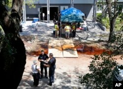 FILE - Police officers talk to an employee at the Rehabilitation Center at Hollywood Hills in Hollywood, Fla., Sept. 13, 2017. Several patients at the sweltering nursing home died in Hurricane Irma's aftermath.