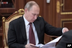 FILE - Russian President Vladimir Putin reads papers during a meeting in the Kremlin, in Moscow, Russia, Jan. 16, 2017.