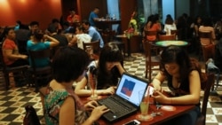 Three young Vietnamese girls use a laptop and smart phones to go online at a cafe in Ha Noi, Viet Nam Wednesday, May 14, 2013. (AP Photo/Na Son Nguyen).