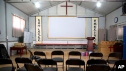 FILE - Calligraphy reading, "All nations belong to the Lord arising to shine," at left, and "Jesus' salvation spreads to the whole world," at right, are displayed in a house church shut down by authorities near Nanyang, China, June 4, 2018.