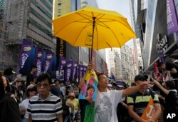 A protester raises a yellow umbrella as thousands of protesters march along a downtown street during an annual pro-democracy protest in Hong Kong Sunday, July 1, 2018.