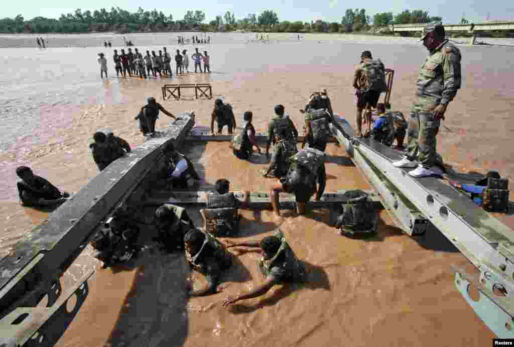 Indian Army soldiers begin work on a temporary bridge across the Tawi river, near the existing bridge which was swept away by floodwaters, Sept. 9, 2014.