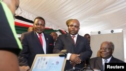 Kenyan President Mwai Kibaki (R) registers as a voter before launching the nationwide, one-month biometric voter registration (BVR) exercise in the capital Nairobi, November 19, 2012, targeting over 18 million voters ahead of the March 4 General Election.