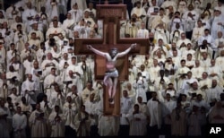 A crucifix hangs above member of the clergy who watch as Pope Francis, not shown, celebrates Mass at Madison Square Garden, New York, Sept. 25, 2015.
