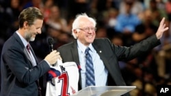 Democratic presidential candidate, Sen. Bernie Sanders, right, waves to the crowd after being presented with a shirt by Liberty President Jerry Falwell Jr., left, during a visit at Liberty University in Lynchburg, Virginia, Sept. 14, 2015.