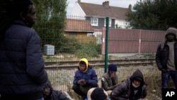 Tampak beberapa migran menunggu untuk mendapatkan makanan di kamp pengungsi di Calais, di sebelah utara Prancis,pada 14 Oktober 2021. (Foto: AP/Christobe Ena)