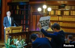 An environmental activist holds a banner reading "resist" while attending a speech by Myron Ebell, left, who leads U.S. President Donald Trump's Environmental Protection Agency's transition team, in Brussels, Belgium, Feb. 1, 2017.