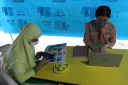Para siswa menggunakan masker agar tidak tertular virus corona sembari belajar secara daring memanfaatkan akses wifi gratis, di Jakarta, 12 Agustus 2020. (Foto: AP)
