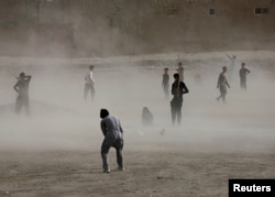 Ko'chada futbol o'ynayotgan afg'on yoshlar