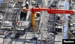 FILE - Labourers work at the construction site of an apartment building in Hanoi, July 1, 2015.