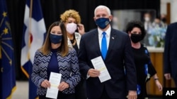 Vice President Mike Pence and his wife Karen walk to cast their ballots during early voting in Indianapolis, Friday, Oct. 23, 2020. (AP Photo/Michael Conroy)